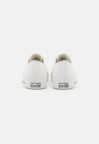 Ein Paar weiße Low-Top Converse All Star Turnschuhe von hinten auf einem weißen Hintergrund abgebildet.