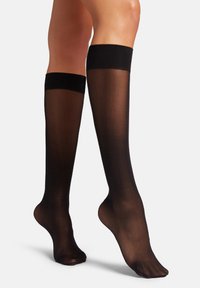 Calze nere fino al ginocchio realizzate in materiale trasparente con una texture liscia e una larga banda nera nella parte superiore per una vestibilità sicura.