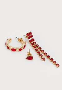 Drie paar oorbellen: een gouden hoop met rode ovale stenen, een rode druppelstud en een lineair ontwerp met meerdere rode stenen gezet in goud.