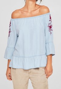 Blusa blu scollo a spalle scoperte con maniche a campana a tre quarti, orlo arricciato e ricami floreali bordeaux sulle maniche. Tessuto in cotone.
