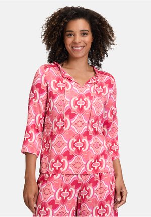 Een hoodie in roze tinten met een gedurfde geometrische print, driekwart mouwen en een relaxed fit. Zachte stoftextuur.