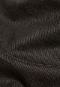 Czarna tkanina o fakturze z gładką powierzchnią, z diagonalnym prążkowaniem i miękkim układem. Odpowiednia na różne elementy garderoby.