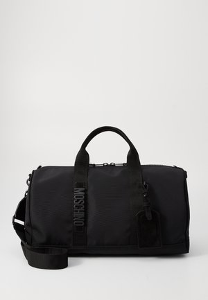Sac de sport noir en nylon avec double poignées, une bandoulière amovible, un logo en relief et une étiquette de bagages. Texture lisse.