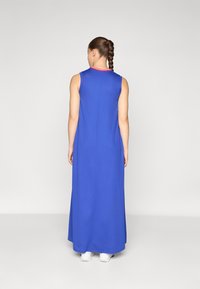 Sleeveless, long blue dress with a simple design. Features a round neckline and a contrasting red trim. Smooth texture, falls to the ankles.