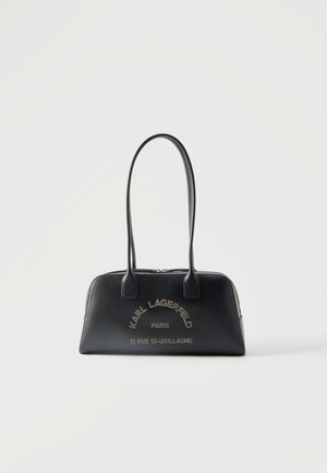 Schwarze rechteckige Handtasche mit langen Griffen, goldener Aufschrift "Karl Lagerfeld Paris" und Adressangabe vorne, Reißverschluss oben, minimalistischer Hintergrund.