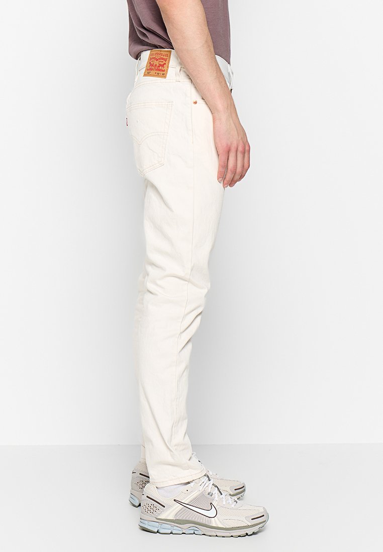 Weiße Denim-Jeans mit schmaler Passform und leichtem Stretch, ausgestattet mit einem klassischen Fünf-Taschen-Design und einem braunen Leder-Logo-Patch an der Taille.