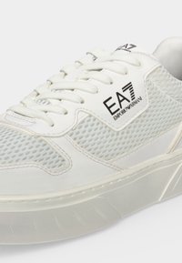 Λευκό sneaker EA7 Emporio Armani με λεπτομέρειες από δίχτυ και δέρμα, κλείσιμο με κορδόνια και παχύ υφασμένο πέλμα.