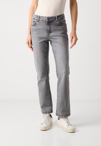 Grå jeans med rett ben, fem lommer, beltehemper og knappeåpning, laget av et mykt denimstoff. Kombinert med hvite joggesko.