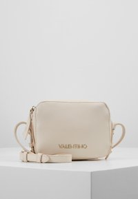 Beige kožená crossbody taška s hrubou texturou, zlatým logem "VALENTINO", zapínáním na zip a nastavitelným popruhem. Minimalistický design.