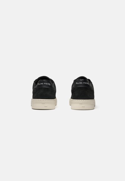 Par sorte ruskindssneakers med beige såler, set bagfra, med "Filling Pieces" branding på hælstrop.