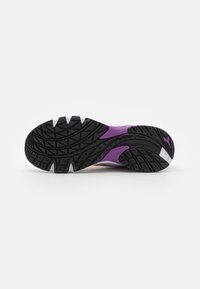 Scarpa sportiva con una suola in gomma nera caratterizzata da un motivo testurizzato, dettagli viola e una parte superiore liscia con un design multicolore.