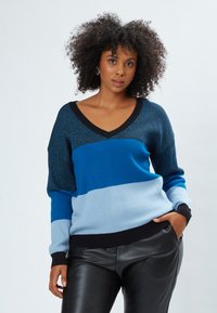 Maglione a righe blu e azzurro chiaro con scollatura a V, texture a maglia e dettagli neri, abbinato a pantaloni in pelle nera.