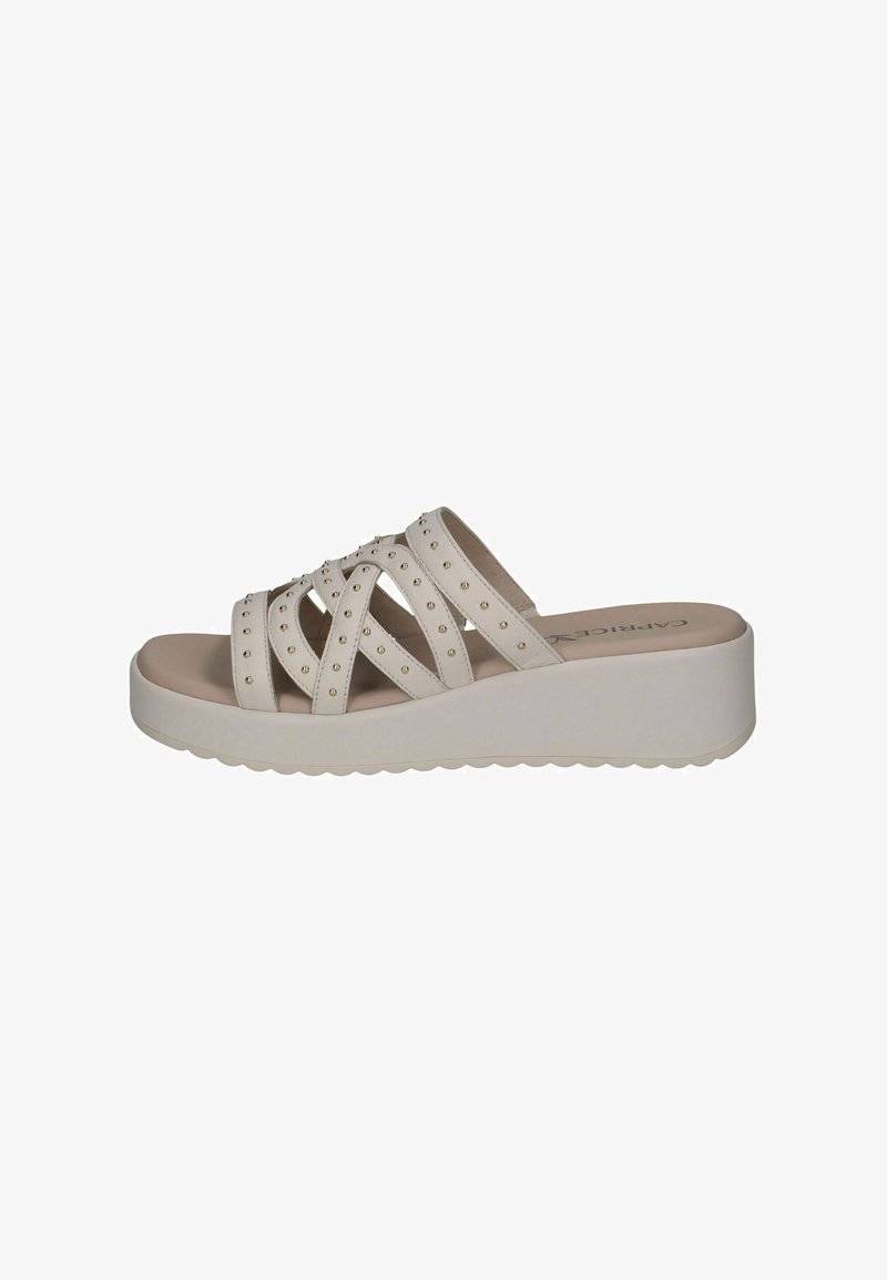 Sandales compensées beiges avec design à brides croisées, ornées de petits clous. Matière lisse et semelle texturée pour une meilleure adhérence.