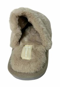 Pantufla beige y peluda con un exterior suave y aterciopelado, diseño fácil de poner, interior acolchado y suela texturizada. Presenta una etiqueta de la marca en la parte superior.