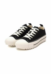 Zapatillas de lona negras con cordones blancos, punta de goma y suela gruesa en zigzag. Incluyen un lazo en el talón y una marca en la lengüeta.