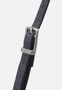 Sort læderrem med en tekstureret finish, forsynet med en sølvfarvet metalspænde med brandingdetalje. Justerbar med flere perforeringer til størrelse.