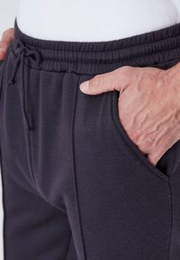 Zwarte sweatpants met een trekkoord in de taille, voorzien van zijzakken en verticale naden voor extra textuur. Zacht, rekbaar materiaal.