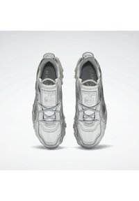 Silberne Sportschuhe aus glattem Material mit gepolsterter Ferse, strukturiertem Sohlen und einem Logopatch auf der Zunge. Komplexes Schnürdesign.