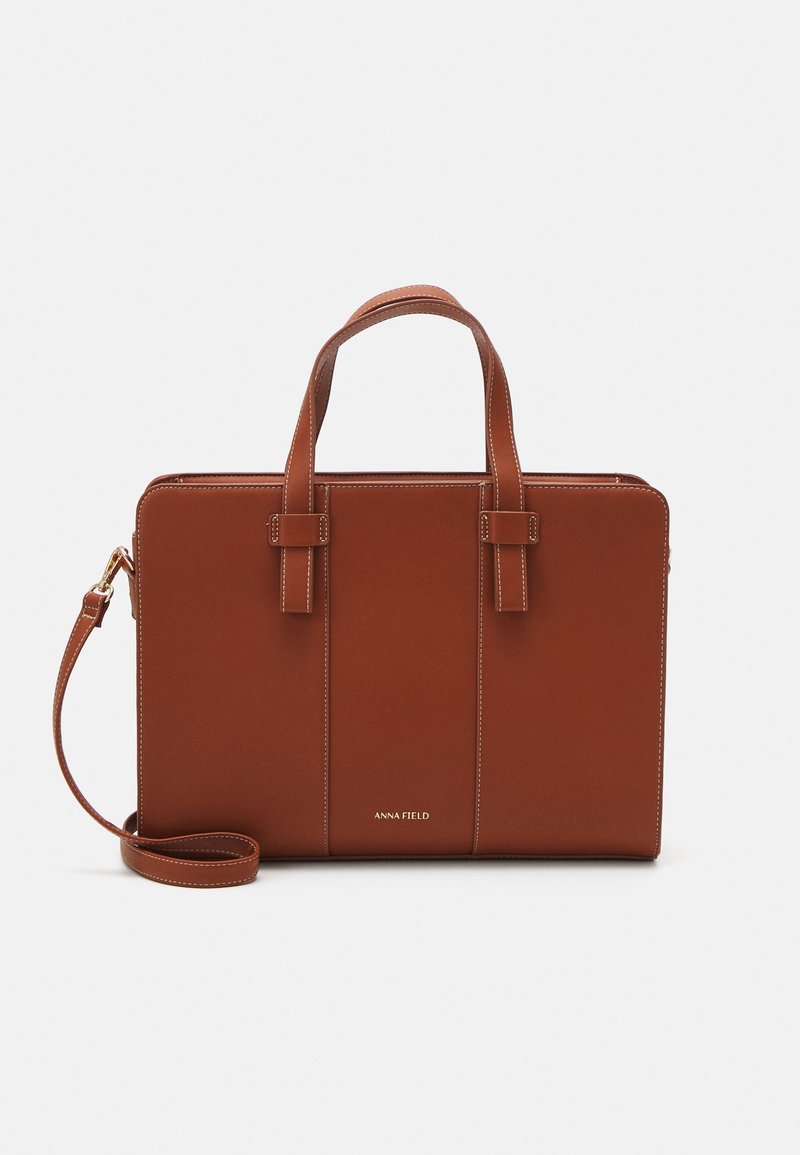 Sac à main en simili cuir marron avec deux anses courtes, une bandoulière réglable et des détails de surpiqûres contrastantes. Logo en relief à l'avant.