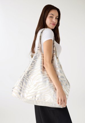 Borsa tote in argento metallizzato e crema con motivo a strisce zebra, dotata di ampie tracolle e forma spaziosa. La superficie strutturata aggiunge interesse visivo.