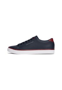 Baskets basses bleu marine avec semelle blanche, bordure rouge, lacets noirs et logo Tommy Hilfiger sur le côté avec un accent rouge au talon.