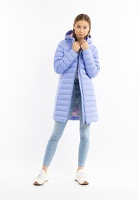 Cappotto lungo imbottito viola chiaro con cappuccio, pattern a righe orizzontali, zip frontale, polsini a coste, indossato sopra jeans blu e sneakers bianche.