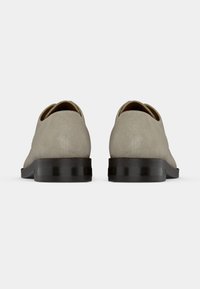 Γκρι σουέτ παπούτσια με στρογγυλή μύτη και χαμηλό μαύρο τακούνι, με απαλό υφή και μινιμαλιστικό σχ έδιο. Χωρίς ορατά σχέδια ή εξαρτήματα.