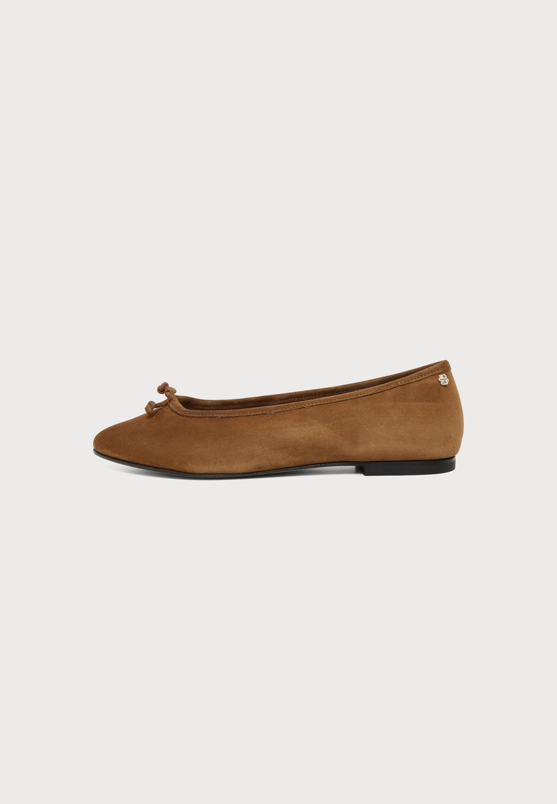 Ballerine en daim marron avec un petit nœud sur le devant et une semelle plate noire sur fond blanc.
