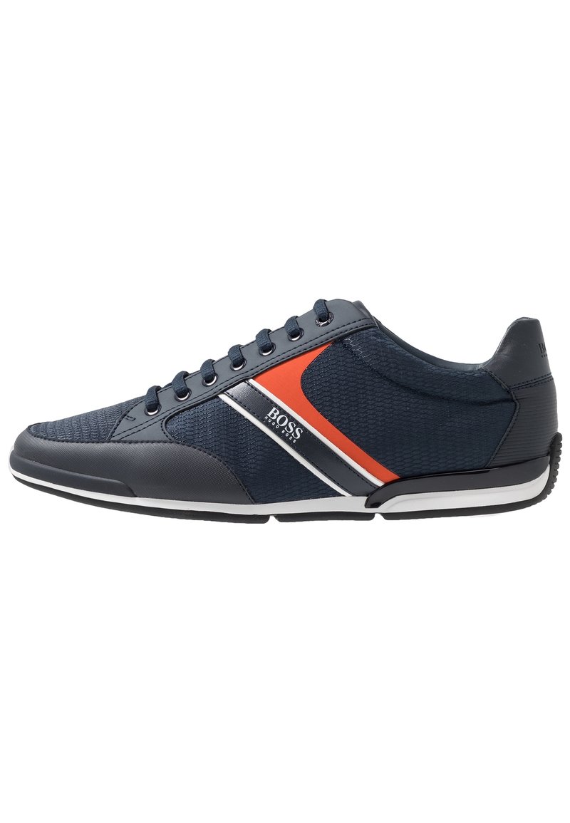 Scarpe sportive blu navy con una tomaia testurizzata, dettagli lisci, strisce rosse e bianche e una suola in gomma nera. Presentano un design con lacci.