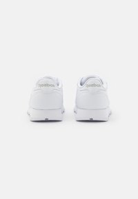 Weisse Reebok Sneaker mit glattem Lederobermaterial, runden Zehen, gepolsterten Sohlen und Logoakzenten an der Ferse und Zunge.