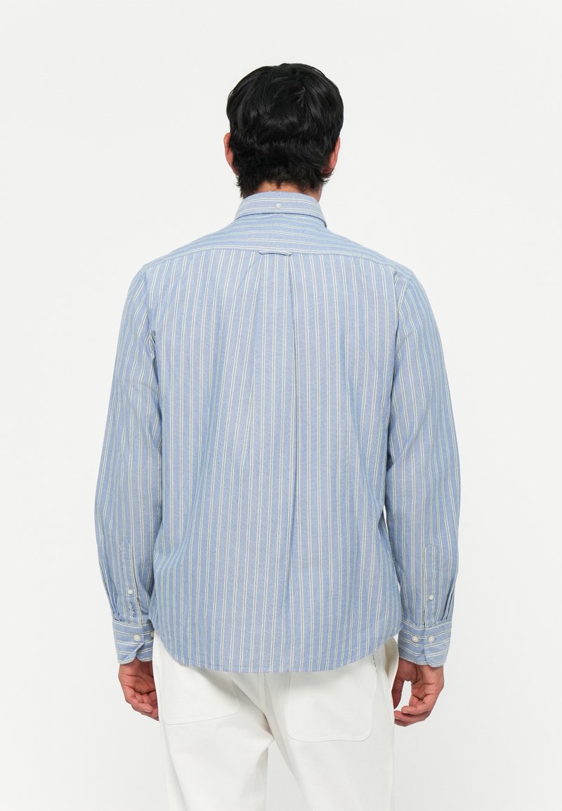 Niebieska i biała w paski koszula z długim rękawem, z kołnierzykiem, zapiętymi mankietami i prostym dołem. Materiał wydaje się miękki i lekki.