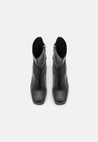 Stivaletti alla caviglia in pelle nera con punta quadrata, texture liscia e dettagli con zip laterale per una facile calzata.