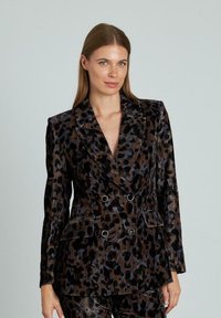 Blazer doppiopetto in stampa leopardata con finitura lucida. Presenta grandi revers, due tasche frontali e accenti metallici.