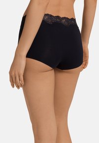 Svarta bomullstrosor med en vågig spetsmidja och en mjuk textur, designade för komfort och blygsam täckning.