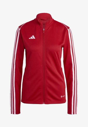 Veste zippée rouge en tissu lisse avec des rayures blanches le long des manches et un col haut. Un logo est également présent sur la poitrine.