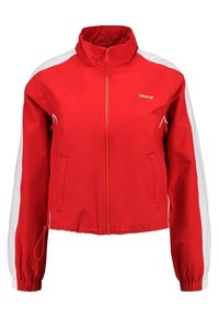 Czerwona kurtka na zamek z białymi bocznymi panelami, wysokim kołnierzem i elastycznymi mankietami. Na piersi znajduje się logo Levi's, a także dwie boczne kieszenie.