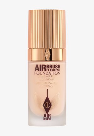 Transparent glass bottle with a gold, ribbed cap. Label features “AIRBRUSH FLAWLESS FOUNDATION” in dark red lettering and decorative emblem.