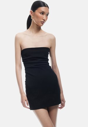 Robe mini noire sans bretelles au design ajusté, réalisée en tissu lisse avec un léger éclat, présentant un décolleté droit et une silhouette près du corps.