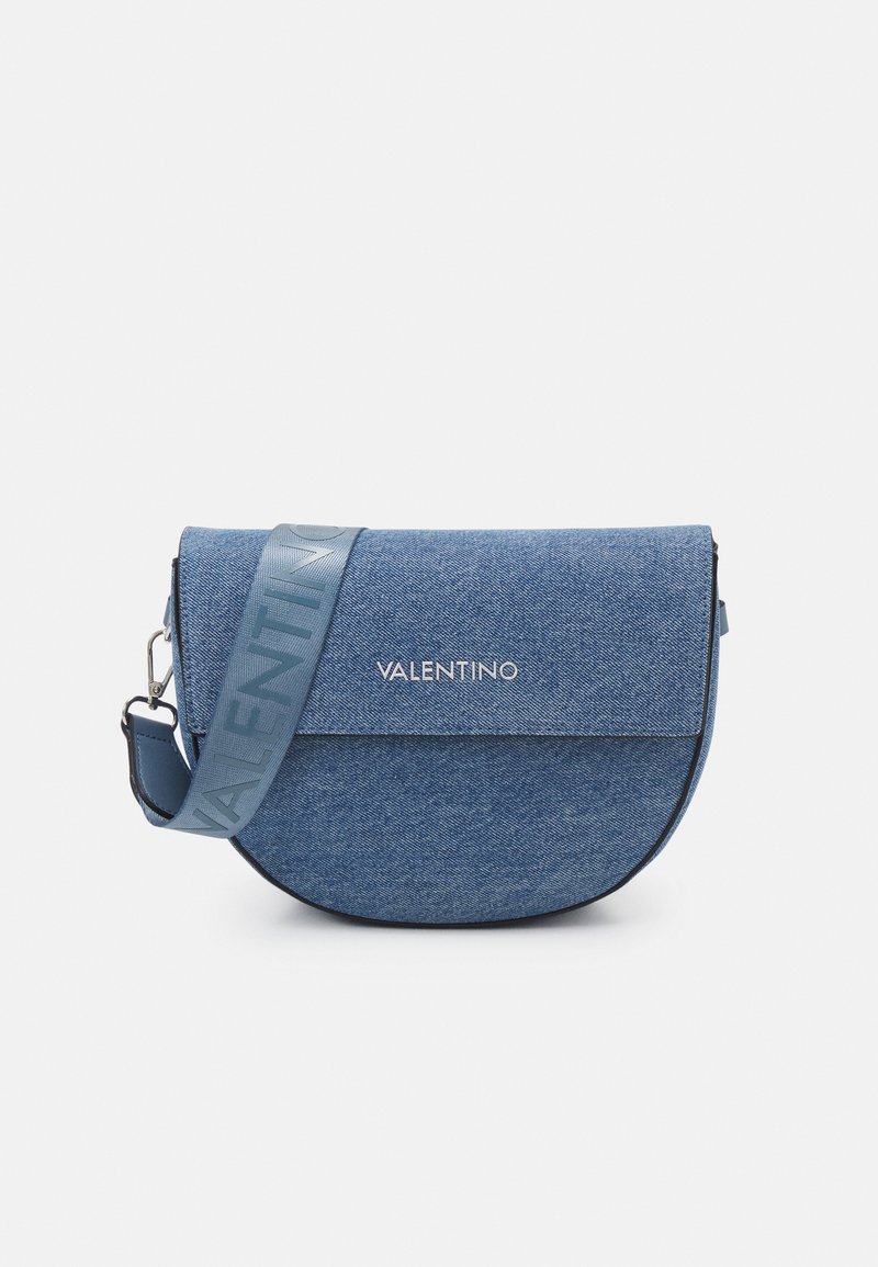 Denim handbag in blue with a half-moon shape. Features a smooth texture, magnetic flap closure, and a wide strap with the "Valentino" logo.