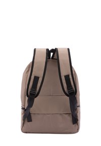 Sac à dos en tissu beige avec des bretelles noires, de forme rectangulaire, et une poche frontale avec une fermeture éclair horizontale. Texture lisse, design minimal.