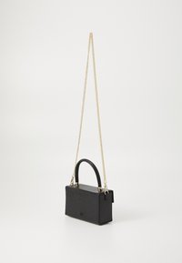 Liten svart håndveske med krokodilleprentasjer, med topphåndtak og en gullkjede-rem. Rektangulær form med metalliske detaljer.