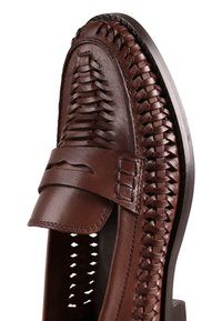 Mocassin pour hommes en cuir marron avec des détails tressés et une bride sur le dessus, présenté en vue rapprochée sous un angle.