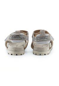 Sandalias de ante en color beige con una suela texturizada y tachuelas decorativas a lo largo de las correas. Diseño de espalda abierta con una plantilla acolchada.