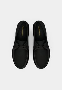 Chaussures noires avec une finition en cuir lisse, forme arrondie, design à lacets et détails de couture visibles, arborant la marque "Copenhagen Shoes" à l'intérieur.