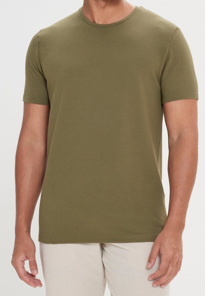 Camiseta de manga corta color verde oliva con un tejido texturizado, escote redondo y silueta ajustada, apta para uso casual.