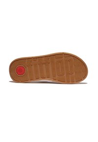 Onderkant van FitFlop-schoenen, met een tan rubberen loopzool met een textuurpatroon voor grip en de merknaam duidelijk geperst.