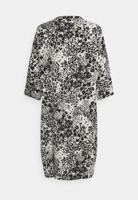 Robe imprimée léopard noir et blanc avec des manches trois-quarts et un col arrondi, fabriquée à partir d'un tissu lisse et léger.