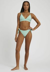 Ensemble de bikini vert menthe comprenant un haut triangulaire avec des rayures verticales et des bretelles ajustables, associé à un bas de bikini noué sur les côtés.