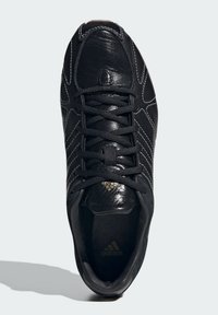 Μαύρο αθλητικό παπούτσι με κομψό δερμάτινο επάνω μέρος, υφασμένο φινίρισμα και αντίθετη λευκή ραφή. Διαθέτει υφασμένο γλώσσα και σχέδιο με κορδόνια.