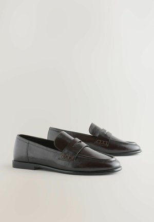 Juodi odiniai loaferiai su elegantišku dizainu, plokščiu padu ir dekoratyvia juostelių detale. Sklandus paviršius su subtiliu blizgesiu ir minimalizmo akcentais.